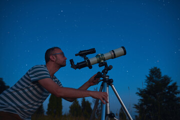 Wall Mural - astronomer looking at the starry skies with a telescope.