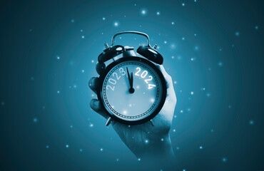 Wall Mural - hand holding alarm clock with 2023 and 2024 for merry christmas and happy new year concept.