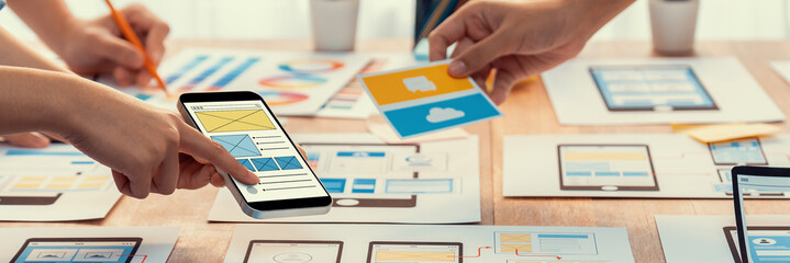 Wall Mural - panorama shot of front-end developer team brainstorming ui and ux designs for mobile app on paper wi
