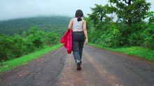 Woman Walking On The Street Covered By Lush Green Trees And Grass On Both Side At Saputara, Gujarat, India. Travelling To Hill Station During Monsoon. Young Woman Exp