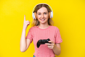 Sticker - Blonde English young girl playing with a video game controller isolated on yellow background pointing up a great idea