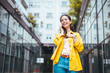 © Dragana Gordic - Smiling young woman with smart phone walking on the street. Happy young woman in casual walking while talking over phone. Cheerful girl using smartphone. Woman talking on phone outdoor.