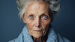 Senior grey-haired blue eyes woman skeptic and nervous, disapproving expression on face on blue background.