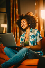 Sticker - Woman sitting on couch with laptop computer in her lap and smiling.