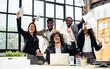 © Ann Rodchua - Group of diverse multiethnic businesspeople wearing formal suits, raising hands, smiling together with happiness and success, standing in modern indoor office after finishing teamwork project.