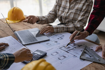 Engineers point to buildings on blueprints and use building design laptops, construction projects of engineers who work on drawings in blueprint meetings for projects, work with modeling partners.