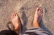 Men's bare feet stand on the sandy beach. Top view, flat lay