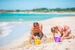 © travnikovstudio - Father with daughter playing with sand on tropical beach. Family playing with beach toys