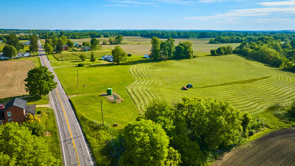 Wall Mural - Bright summer day with tractor harvesting field aerial