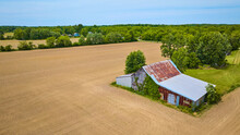 Rusty Old Barn Surrounded By Flat Farmland With No Crops And Smoothed Out Dirt Aerial
