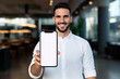 Satisfied smiling man showing mobile phone blank white screen mockup to camera. High quality photo