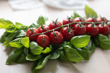 Fresh Italian sweet basil and tomatoes on a kitchen table in front of an open window at sunset