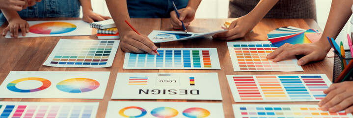 Leinwandbilder - Graphic designer brainstorm logo and graphic art at busy creative studio workshop. Experiment and brainstorm color palette and pattern at workspace table for creative design. Panorama shot. Scrutinize