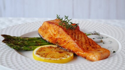 Wall Mural - grilled fillet salmon with asparagus, tomato, lemon, white sauce on plate,  rotates 360 degrees, close up