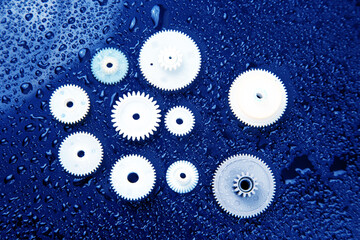 white plastic gears on a dark background. connection mechanism details. subject of movement
