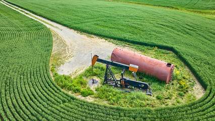 Wall Mural - Oil pump jack and tank in field with maintenance road aerial