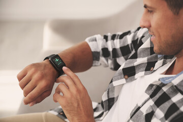 Poster - Man setting smart home control system via smartwatch indoors. App interface with icons on display