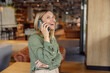© Daria - Smiling businesswoman is talking phone with client while standing on modern coworking background