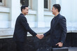 © Queenmoonlite Studio - Two business colleagues shaking hands outdoors. Handshake between two businessmen. Greeting, dealing, merger and acquisition concepts