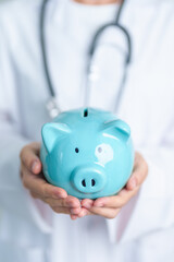 Doctor holding piggy bank and putting coin. and Healthcare cost, Money Saving, Health Insurance, Medical, Donation and Financial concepts