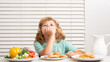 Funny blonde little boy having breakfast. Milk, vegetables and fruits healthy food nutrition for children.