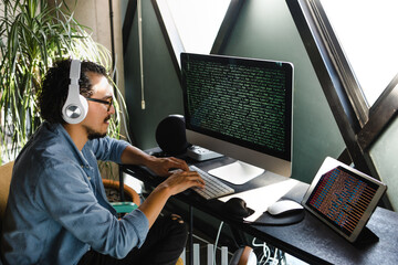 latin man programmer writing program code on desktop computer sitting at the workplace at home in Mexico Latin America, hispanic people