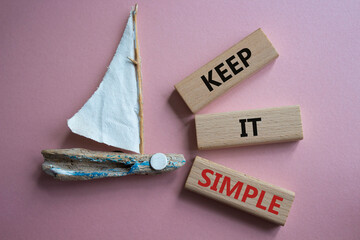 Keep it Simple symbol. Concept words Keep it Simple on wooden blocks. Beautiful pink background with boat. Business and Keep it Simple concept. Copy space.