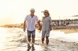 © weyo - A middle-aged couple walking hand in hand on the beach at sunset