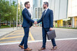© Volodymyr - Businessmen in suit shaking hands outdoors. Handshake between two businessmen. wo business men had business contacts. Business men have a meeting outside. Greeting, dealing, merger and acquisition.