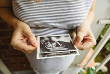 Pregnant Woman Holding Ultrasound Picture At Home