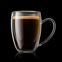 Transparent double wall glass mug full of espresso coffee on black background.