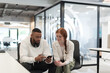 © .shock - In a modern office African American young businessman and his businesswoman colleague, with her striking orange hair, engage in collaborative problem-solving sessions