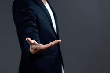 Businessman hold out one's hand against on dark background.