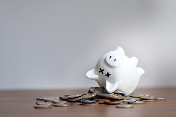 the dead piggy bank lies upside down on coins, economic crisis, decrease, layoff, job fired, pay cut