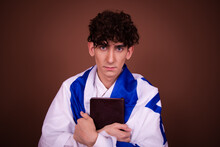 Religion, Culture And Memory Of The Past. Attractive Guy Posing With The Israeli Flag On A Brown Background.