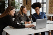 © Drobot Dean - Three smiling women using laptop while working together in office