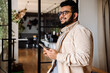 © Drobot Dean - Young indian business man using smartphone while standing in office