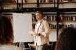 © Drobot Dean - Adult man making presentation at whiteboard in library