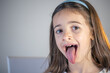 A child girl open her mouth and show her tounge.