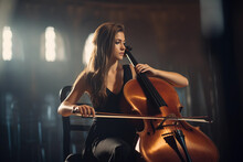 Female Cellist Practicing In An Empty Concert Hall, Her Passion Visible In Her Concentrated Expression, Majestic Architecture, Natural Light Streaming In