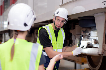 Young caucasian engineer man and woman meeting and checking electric train for planning maintenance in station, transport and infrastructure, inspector or technician talking and check transport.