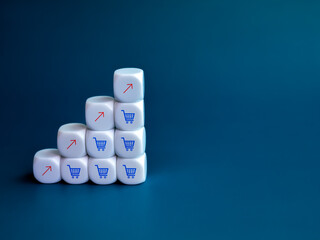 Wall Mural - Red rise up arrow and blue shopping cart trolley icons on white cube block stack as a growth graph steps on blue background with copy space. Online shopping and business increase sales profit concept.