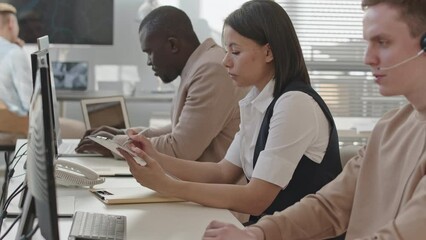 Waist up slowmo of team of young professional diverse security service specialists sitting by desktop computers in office monitoring data from CCTV cameras
