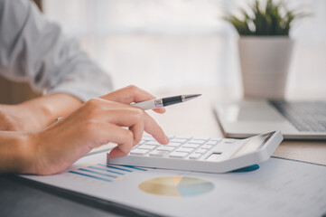 close up The business person is sitting on a calculator with a graph in the office of finance accounting concept