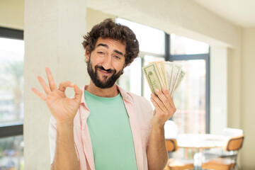 Wall Mural - crazy bearded man feeling happy, showing approval with okay gesture. dollar banknotes concept