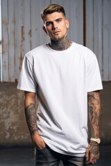 Wall Mural - Oversize white style t-shirt mockup photo with handsome man with tattoos and light concrete background