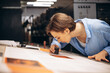 © Petro - Woman typographer working in printing house with paper and magnifying lens