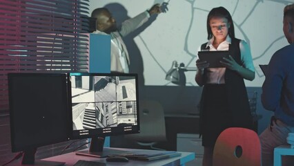 Medium slowmo of multiracial team of professional security agency workers examining city map on projector screen in dark office