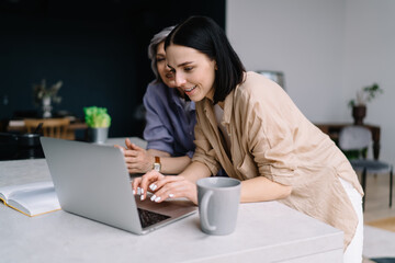 Wall Mural - Content women messaging on laptop in modern office