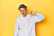 Middle-aged man posing on a yellow backdrop showing thumb down, disappointment concept.
